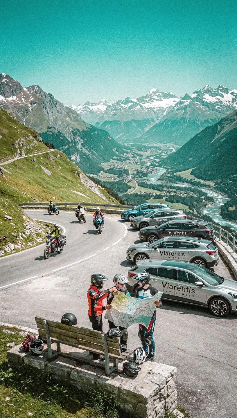Ein Mietwagen steht an einem idyllischen See mit Bergen im Hintergrund.